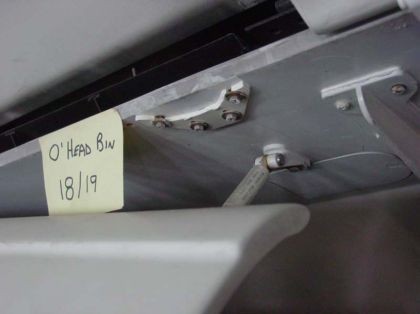 Photo 38. Fractured aft hinge of overhead bin at row 18/19 DEF