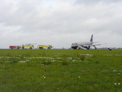 1. Photograph of UAL flight 497 in the grass on the left side of MSY Runway 19. Note: Slide/rafts 1L and 2L are deployed.