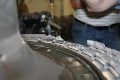 Photo 8: Front 2nd stage turbine blade retaining plate that was buckled (P&W) The rim of the 2nd stage turbine blade rear retaining plate in the area of the missing 2nd stage turbine blades was heat discolored. The 2nd stage turbine blade r
