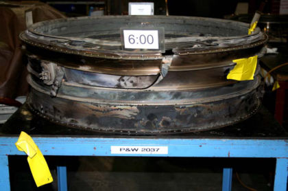 Photo 9: View of tab of displace material on ruptured HPT case (P&W) The upper HPT ACC air duct had the locating bushing broken off. The bracket on the lower HPT ACC air duct was pulled out and remained attached to the upper duct. The lower
