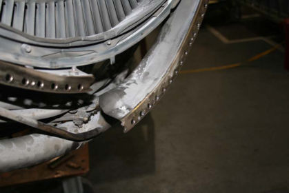 Photo 21: View of LPT case showing displacement of fractured front flange (P&W) The LPT shaft was intact. The LPT shaft had four 360 degree circumferential rub marks. There was a 1/8-inch wide rub mark at 14 13/16 inches from the rear face,