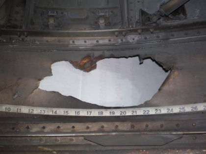 Photo 31: Hole in left core cowl There were several pieces of metallic debris found inside the core cowl. Some of the debris was confirmed by part number and visual comparison to be 2nd stage turbine outer air seal segments.
