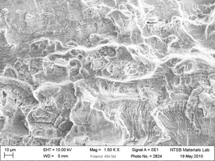 Figure 15: SEM micrograph of the lower stop bracket from N414WF. Fatigue cracks propagating from the outer and inner bends met along the black line in the figure. Arrows